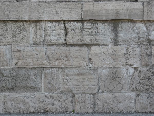 Aged white stone wall with dirt in cracks.